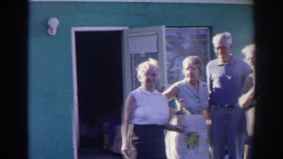 Four adults in 1960s casual clothing stand outside a green building in Norfolk, Virginia, with one woman holding a bottle.