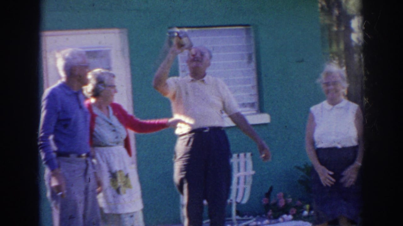 Several older adults stand outside as one man drinks from a bottle.