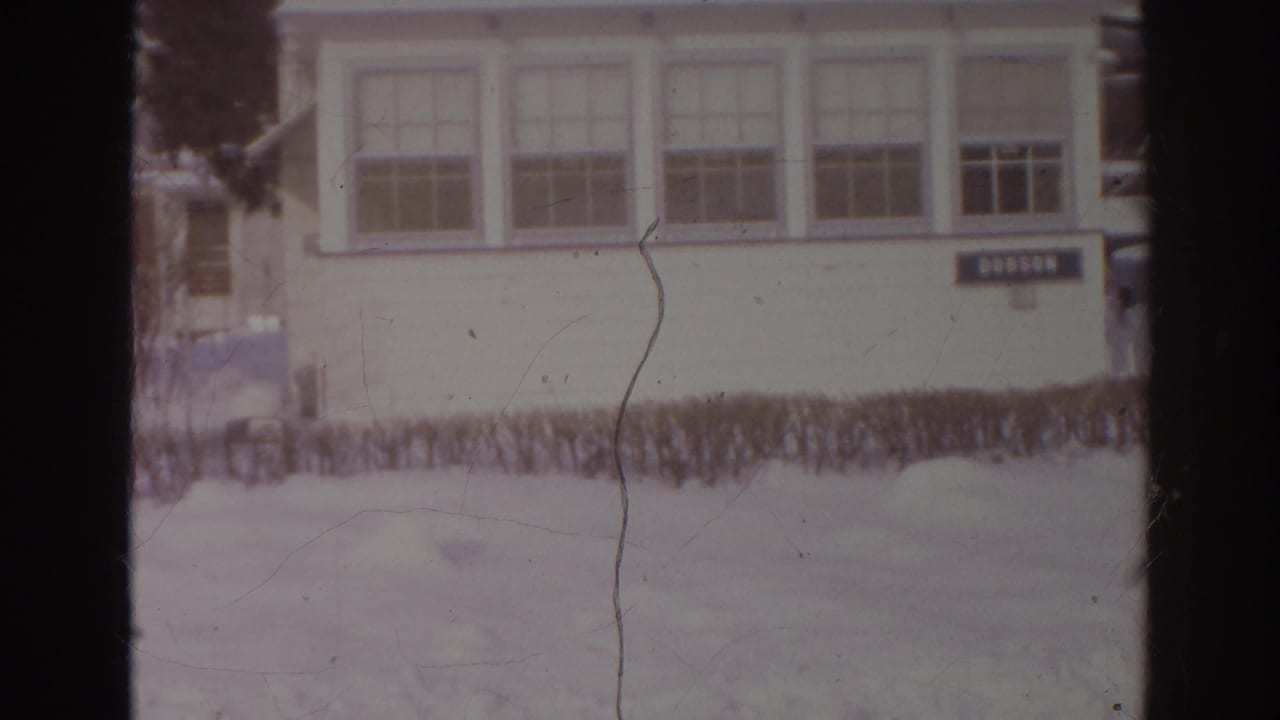 Snowy yard outside a white building with a DOBSON sign and multi-pane windows.