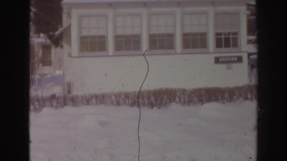 1966 Norfolk, Virginia 8mm frame showing snow in front of a white building with multi-pane windows and a DOBSON sign.