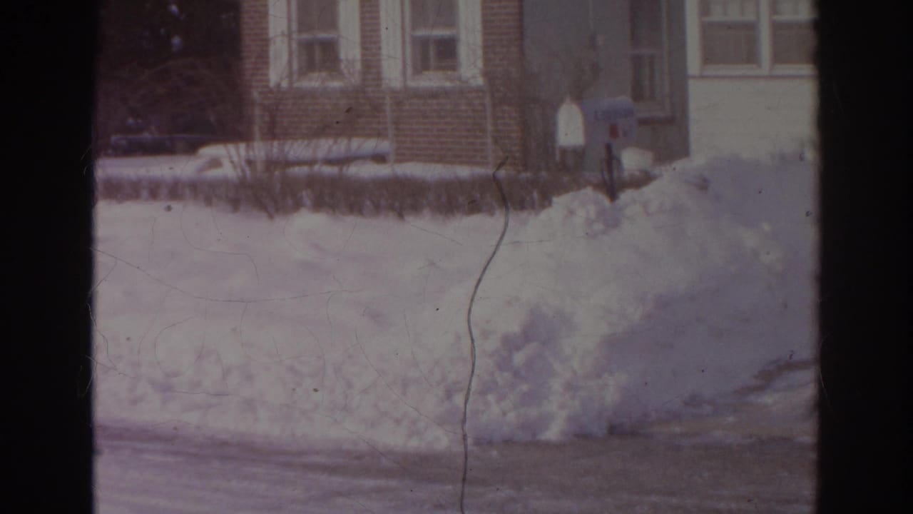 1966 Norfolk winter frame with a high snowbank, brick residential buildings, curbside mailboxes, and a partially cleared street.