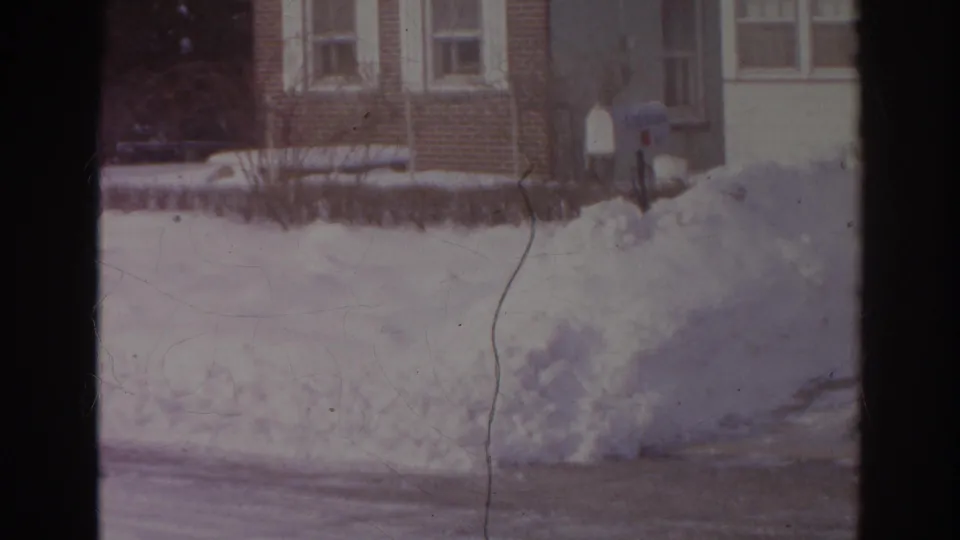 1966 Norfolk winter frame with a high snowbank, brick residential buildings, curbside mailboxes, and a partially cleared street.