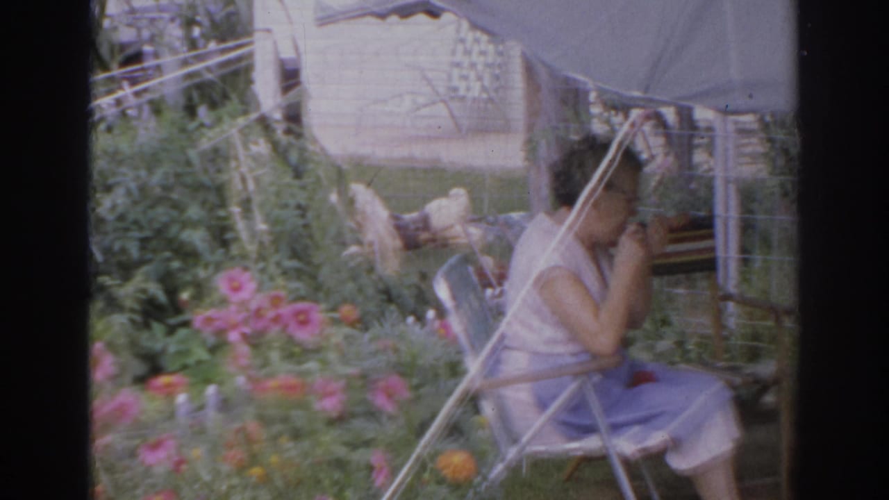 Woman smoking in a folding chair under a patio umbrella.