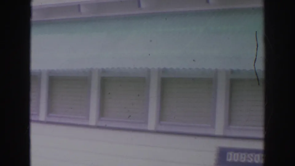1966 Norfolk 8mm frame showing a white clapboard building with green awnings and shuttered upper windows.