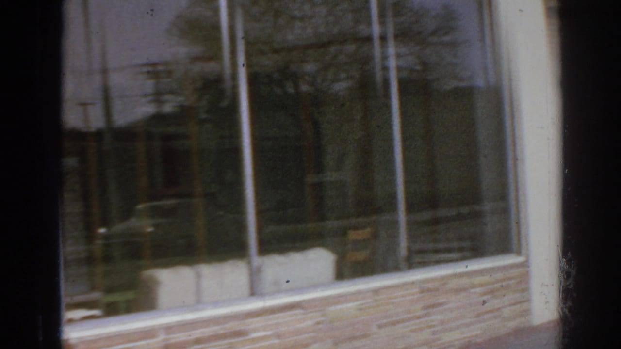 San Gabriel commercial frontage with plate-glass windows, brick base, reflections, and a partially visible Mexican food sign.