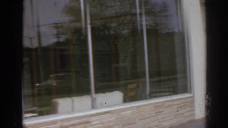 San Gabriel commercial frontage with plate-glass windows, brick base, reflections, and a partially visible Mexican food sign.