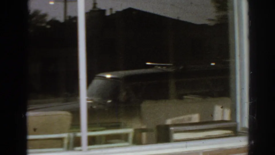 Plate-glass storefront window in San Gabriel reflecting a car, trees, and surrounding buildings during the 1966 street pan.