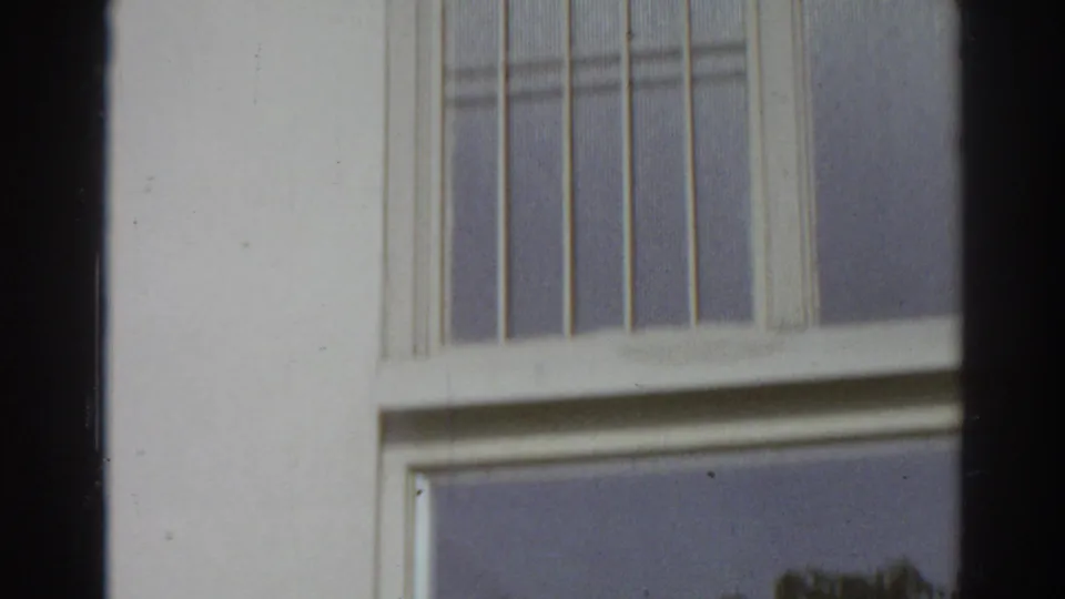 San Gabriel 1966 frame showing a close residential window and pale wall, with vertical bars or mullions visible.