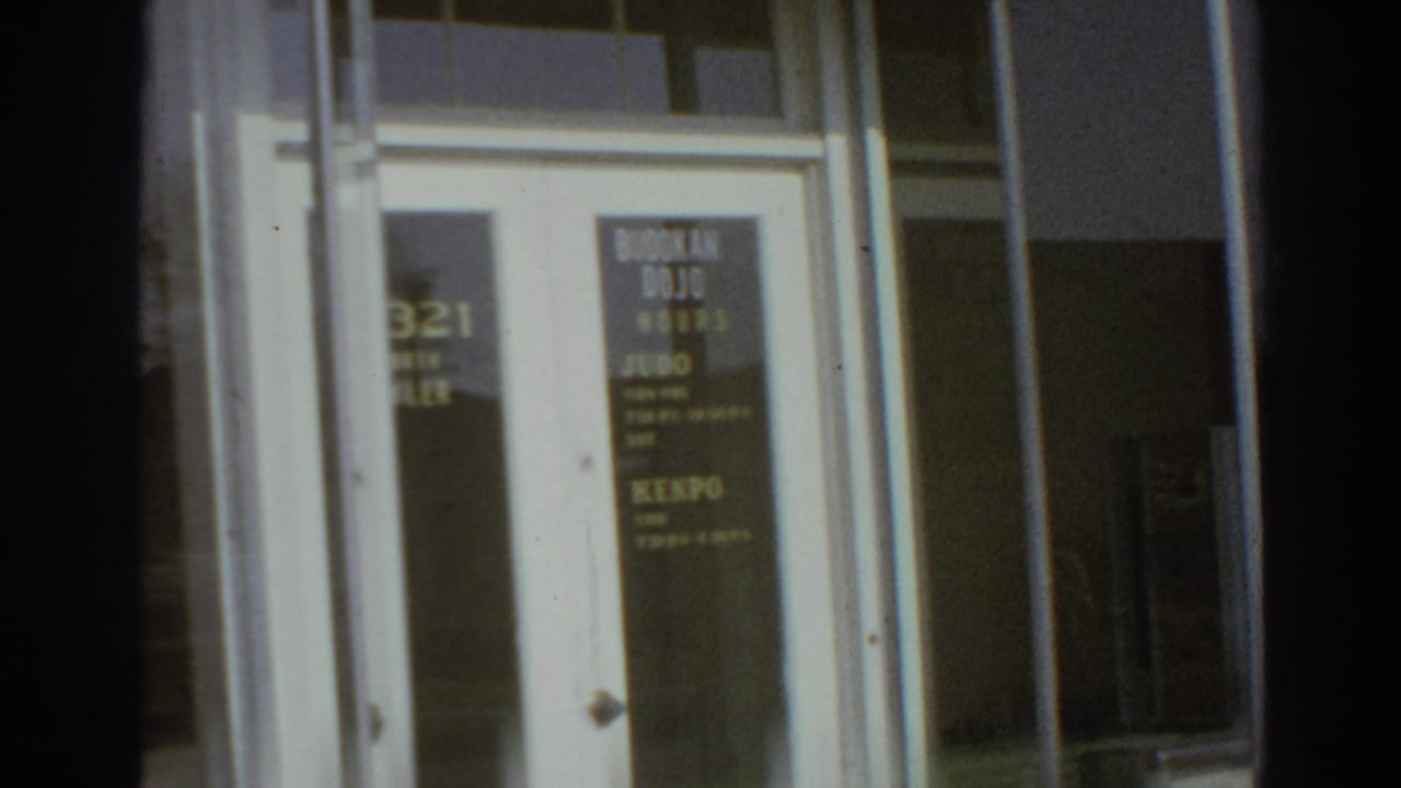 Glass entry to the San Gabriel Budokan dojo with posted class lettering and a Kenpo sign visible on the door.