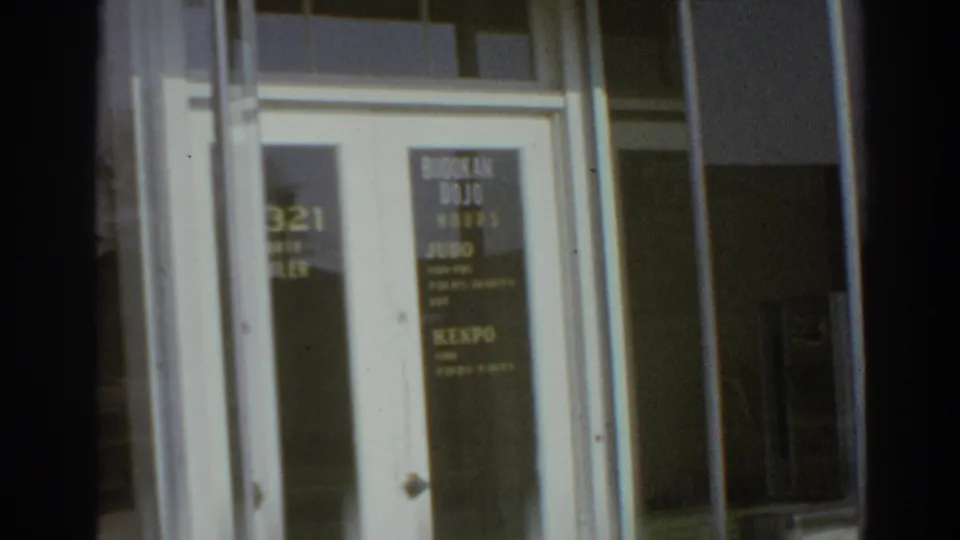 Glass entry to the San Gabriel Budokan dojo with posted class lettering and a Kenpo sign visible on the door.