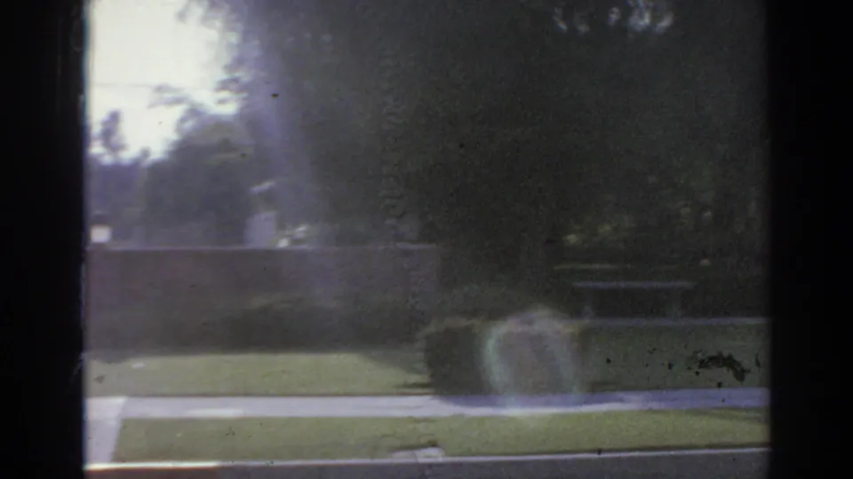 San Gabriel landscaped exterior with lawn, sidewalk, low wall, trees, and soft 8mm exposure in a 1966 home-movie frame.