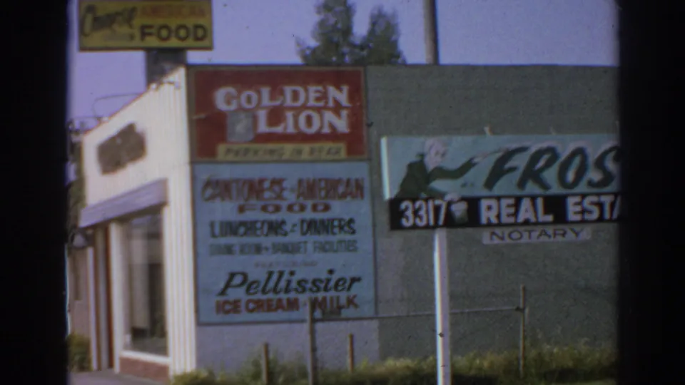 1966 San Gabriel street frame with Golden Lion, real estate and notary, food, and ice cream or milk signage on adjacent storefronts.