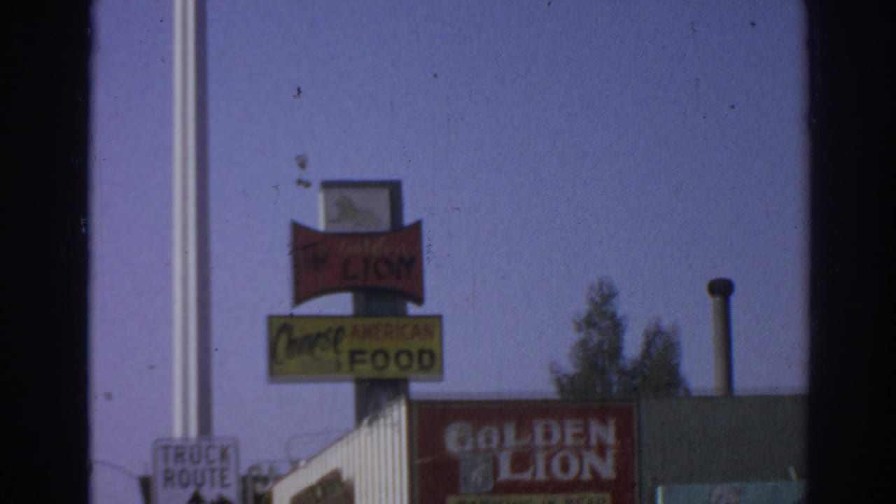 1966 San Gabriel view of stacked roadside signs, including Golden Lion and Chinese American Food, with storefront rooflines behind.