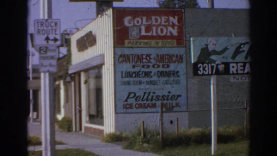 1966 San Gabriel frame with a Truck Route sign at left and Golden Lion restaurant signage across the storefront corner.