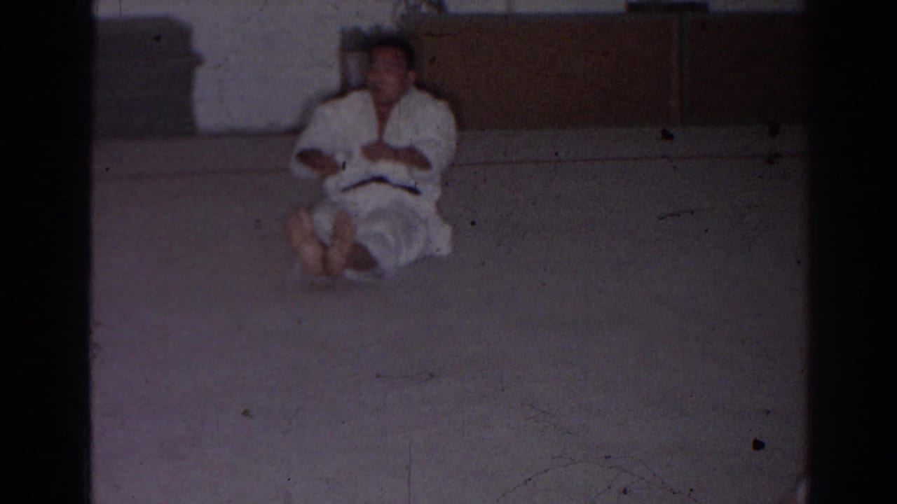San Gabriel 1966 frame of a martial arts student seated on a padded dojo floor during a home-movie lesson.