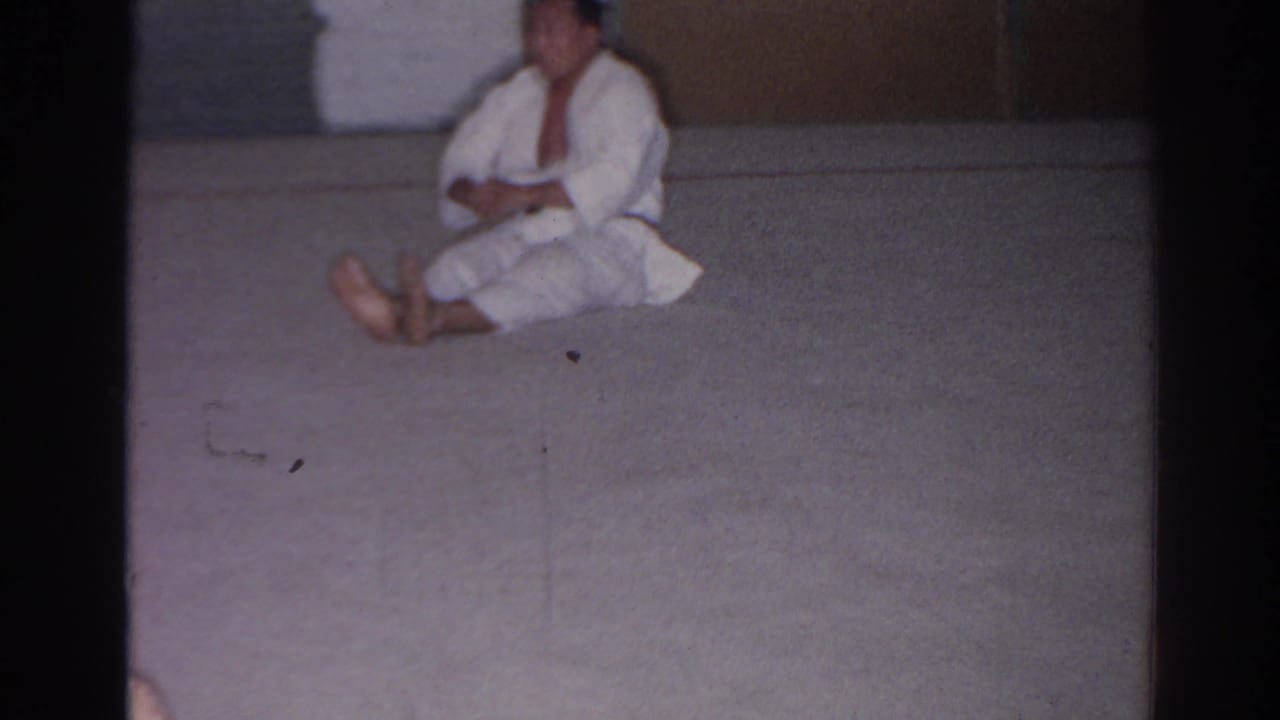 The practitioner sits upright on the mat during a sit-up in the San Gabriel indoor training space.
