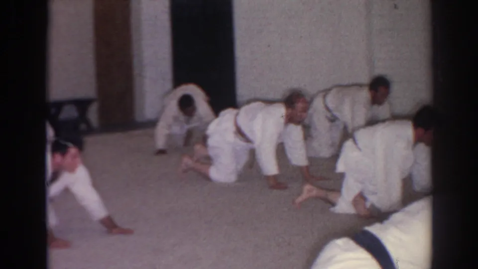 In San Gabriel, California, 1966, men in white martial arts uniforms appear to practice floor drills in a plain indoor room.