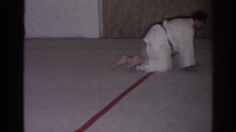 A 1966 San Gabriel frame shows a martial arts practitioner kneeling near the edge of a carpeted training area.