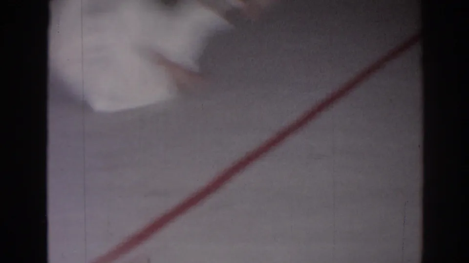 1966 San Gabriel home-movie frame showing a blurred judo uniform near a red mat line during practice.