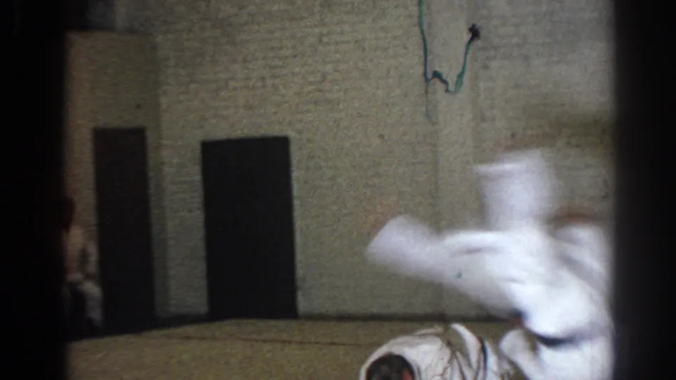 1966 San Gabriel dojo frame capturing a motion-blurred leap over a crouched martial arts participant.
