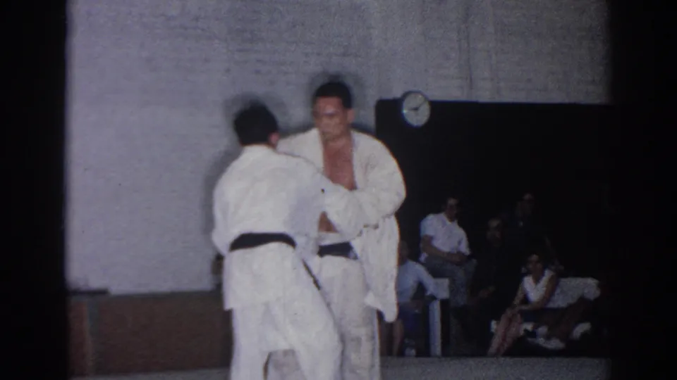 A black-belt competitor faces toward the camera as his opponent turns away during the short San Gabriel tournament match.