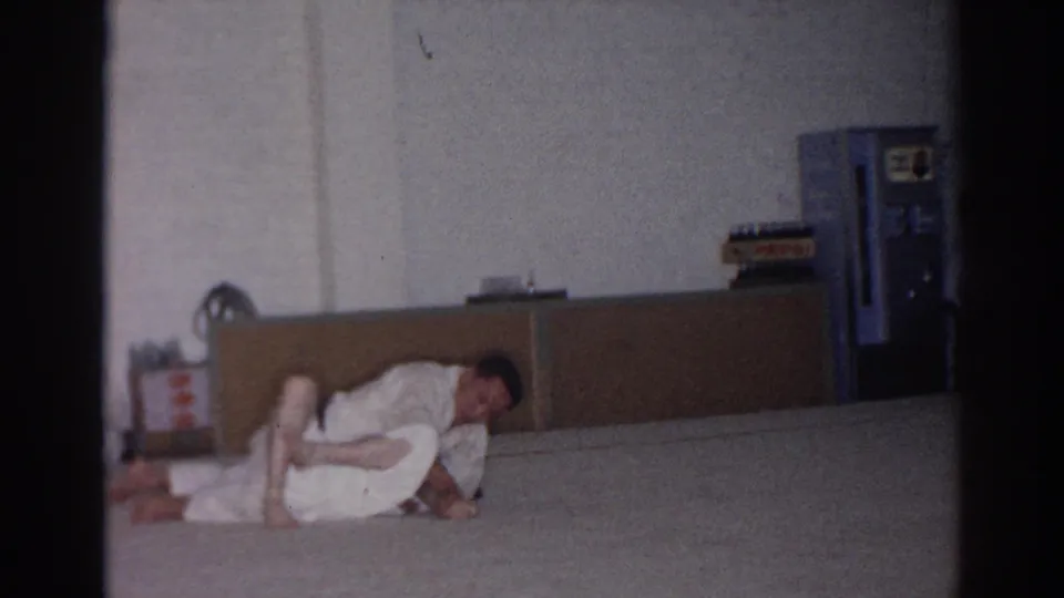 Near the end of the 1966 San Gabriel clip, the gi-clad men roll lower on the padded floor, with the simple training room visible behind them.