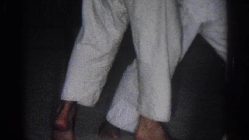 1966 San Gabriel 8mm frame showing two martial arts practitioners in white gi uniforms during close movement indoors.