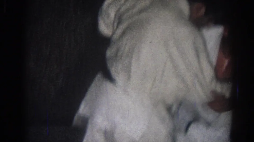 In the supplied 1966 San Gabriel footage, two adults in white gi appear mid-grapple in a dim indoor martial arts practice space.