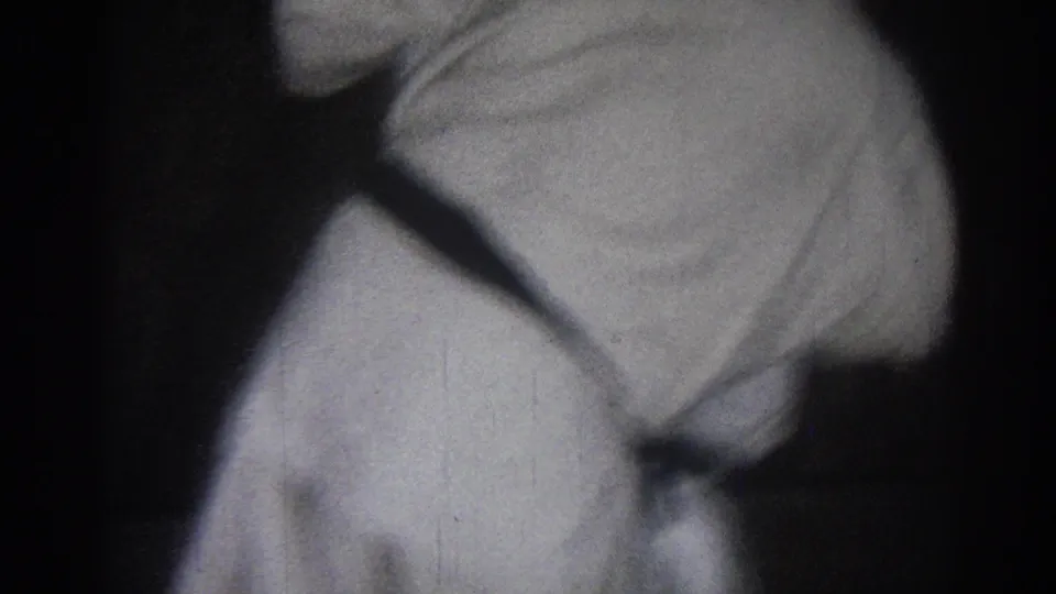 Two practitioners in white martial arts uniforms appear in a low, cropped training moment on a dark indoor floor.