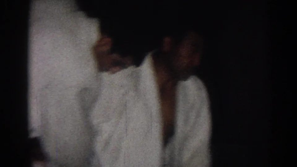 A karate student in a white gi appears in profile during practice, filmed in low light in San Gabriel, California, 1966.