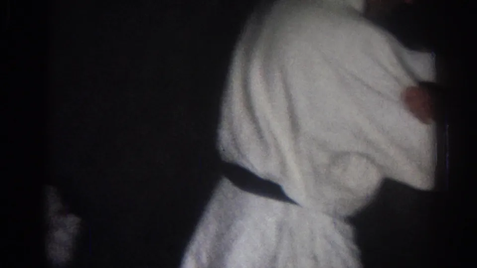 A practitioner in a white uniform turns or steps through a martial arts motion in the dim 1966 San Gabriel footage.