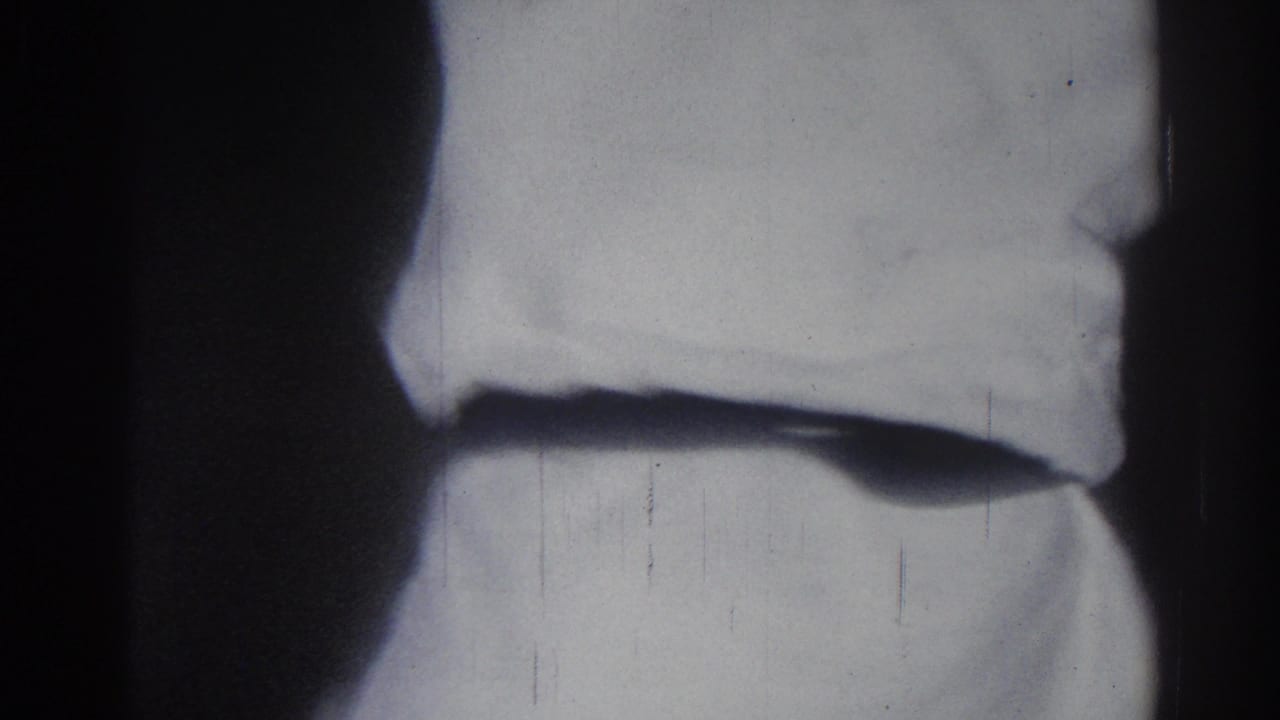 Two figures in white martial arts uniforms stand close together in a dark indoor space.