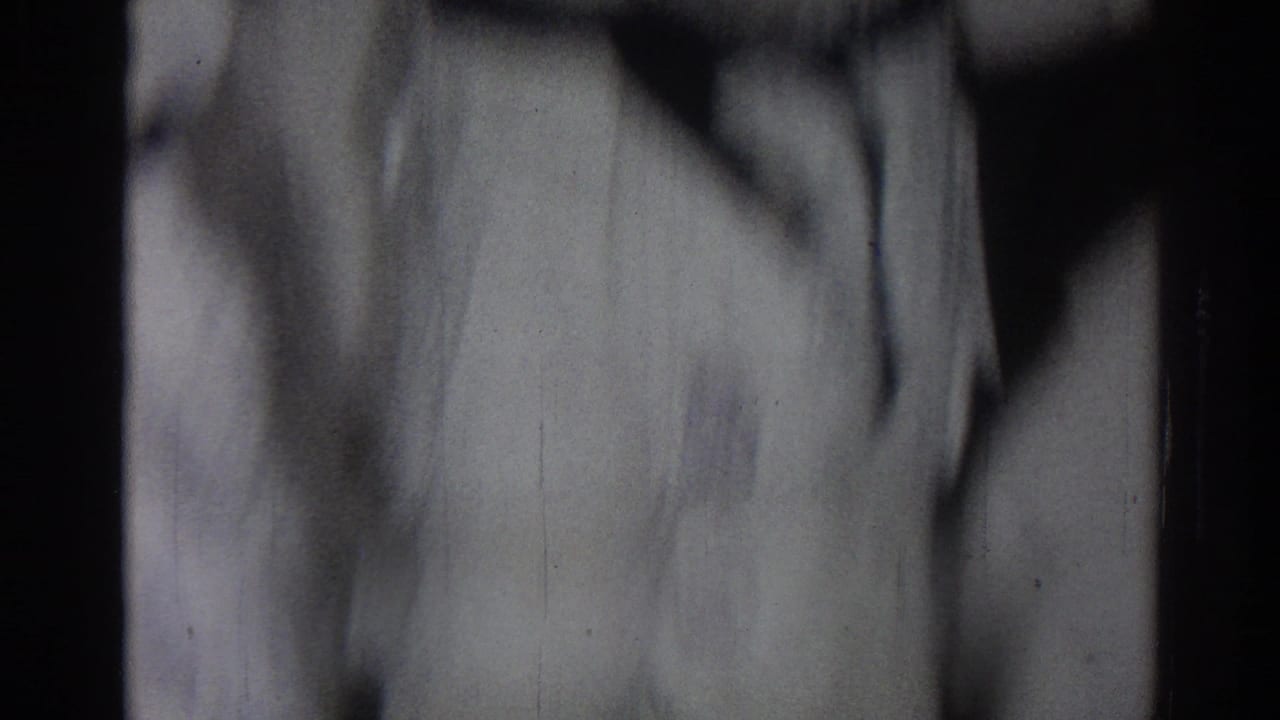 Blurred person in a white martial arts robe against a dark indoor background.