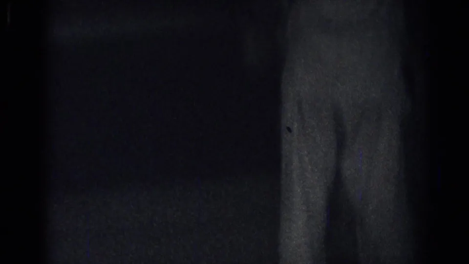 A dim interior frame from the karate practice clip shows little detail beyond a shadowed wall edge.
