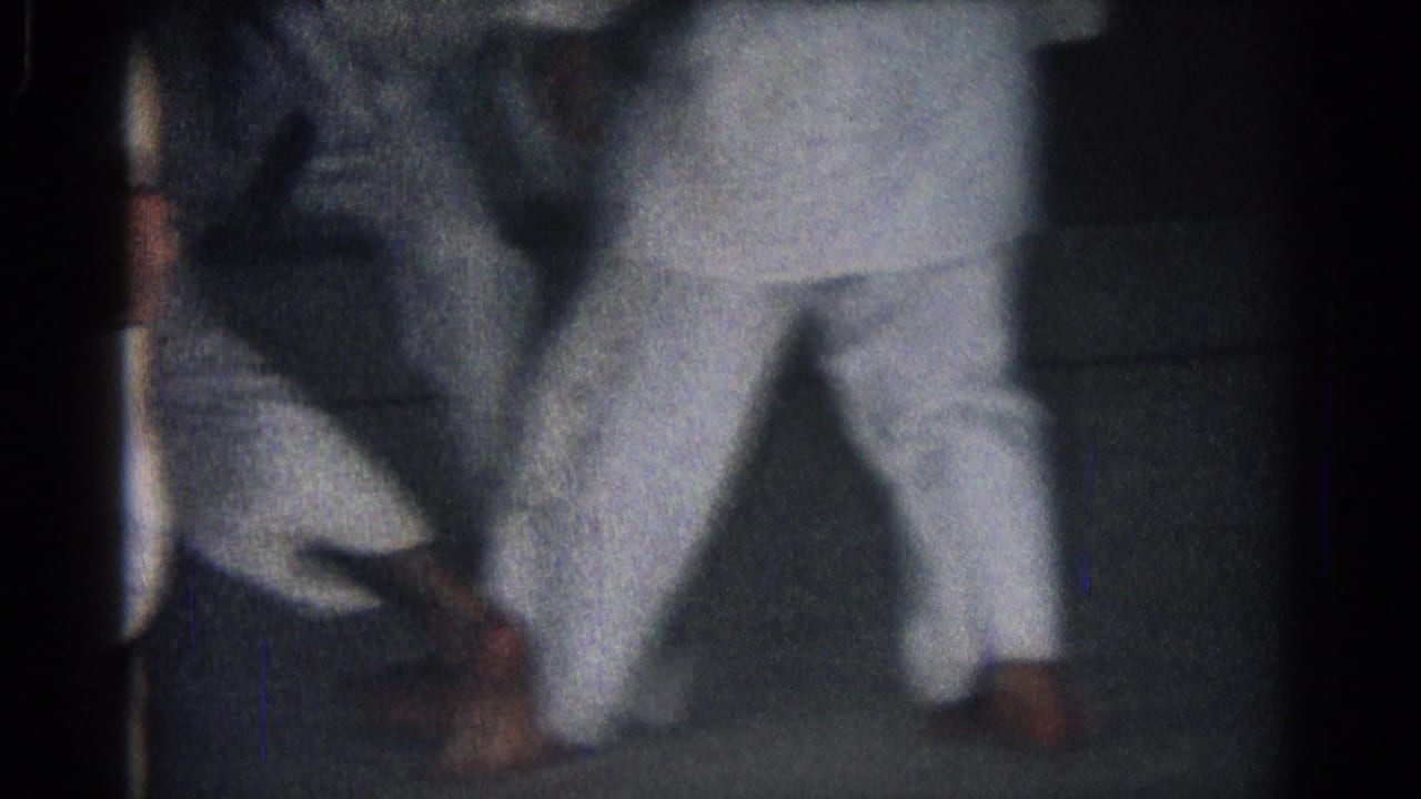 1966 San Gabriel 8mm frame with two black-belt practitioners in white gi uniforms engaged in close sparring movement.