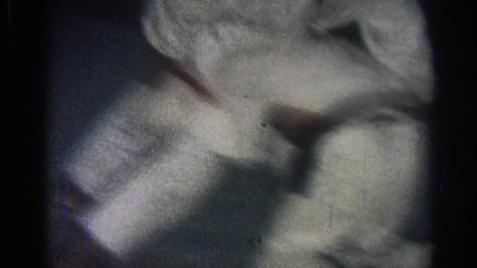 Close 8mm frame from the San Gabriel clip showing white gi fabric and limbs compressed during a martial arts ground hold.