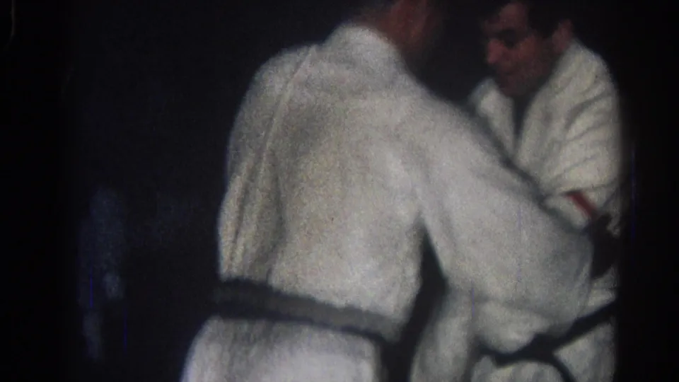 Two adult men in white judo gis face each other closely during a 1966 indoor practice in San Gabriel, California.