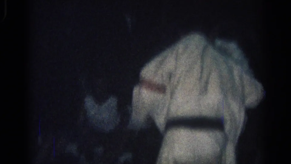 A dim 1966 San Gabriel frame shows a martial arts participant in a white gi bent forward, with another figure partly obscured nearby.