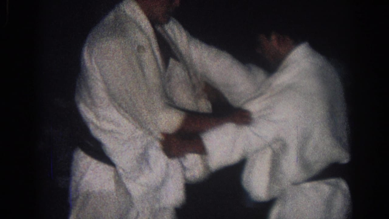 Two judo practitioners lean into a close standing grip.