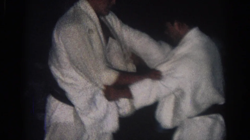 Two men in white gis lean forward in a standing judo grip, with the San Gabriel 1966 setting supported by clip metadata.