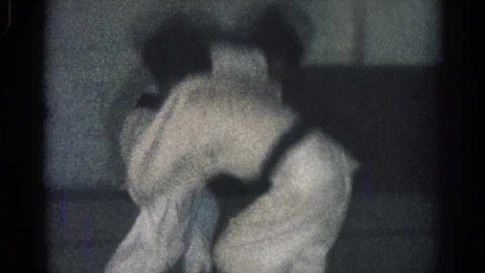 During the brief 8mm sequence, one judo practitioner bends low as the other moves through a throw or takedown motion.