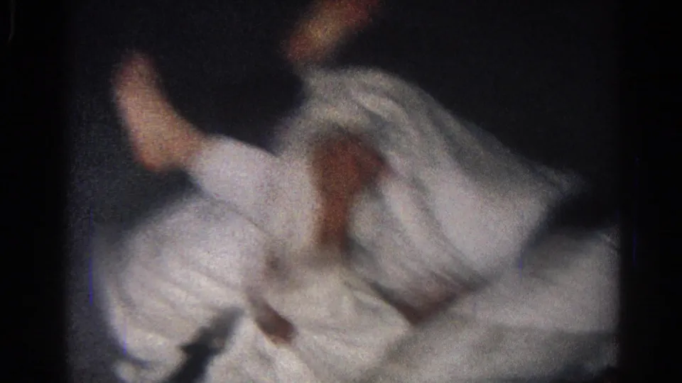 In 1966 San Gabriel home-movie footage, two men in white gi uniforms appear to grapple on the floor under low light.