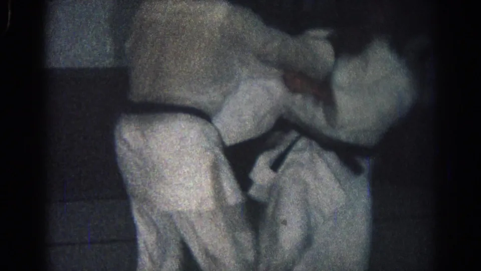Two gi-clad men continue a ground exchange in the 1966 San Gabriel footage, with one body partly over the other.