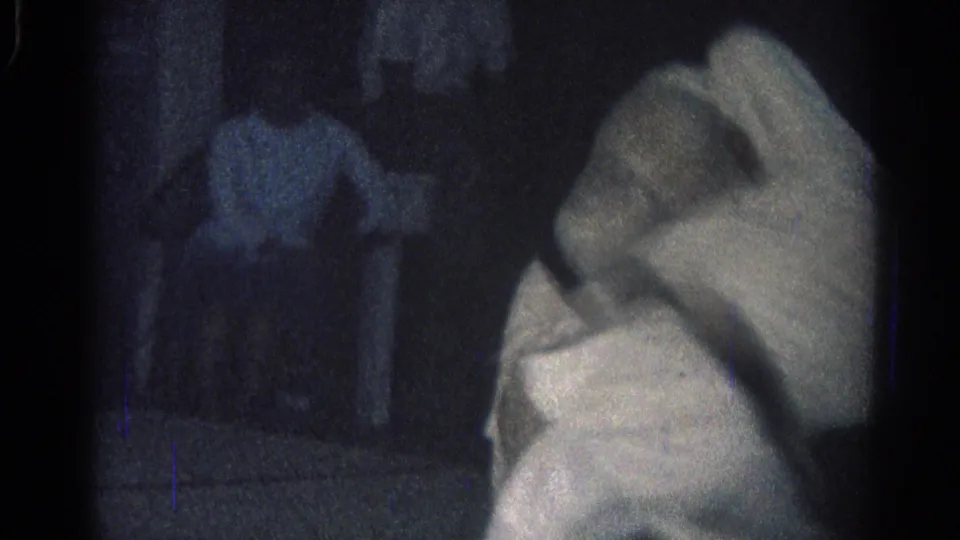 A gi-clad man bends forward near the camera while another person stands in the shadowed background of the San Gabriel scene.