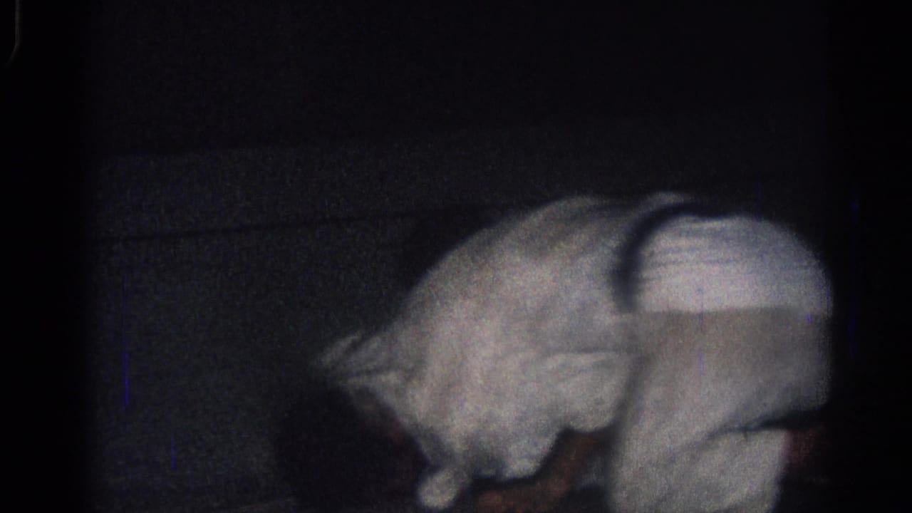 1966 San Gabriel frame with a white-uniformed martial artist leaning forward during a ground grappling exchange.