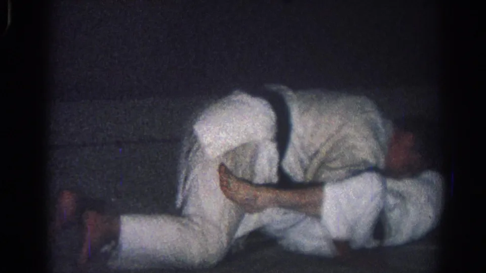 1966 San Gabriel 8mm still of two martial artists in white uniforms tangled together in a low ground hold.