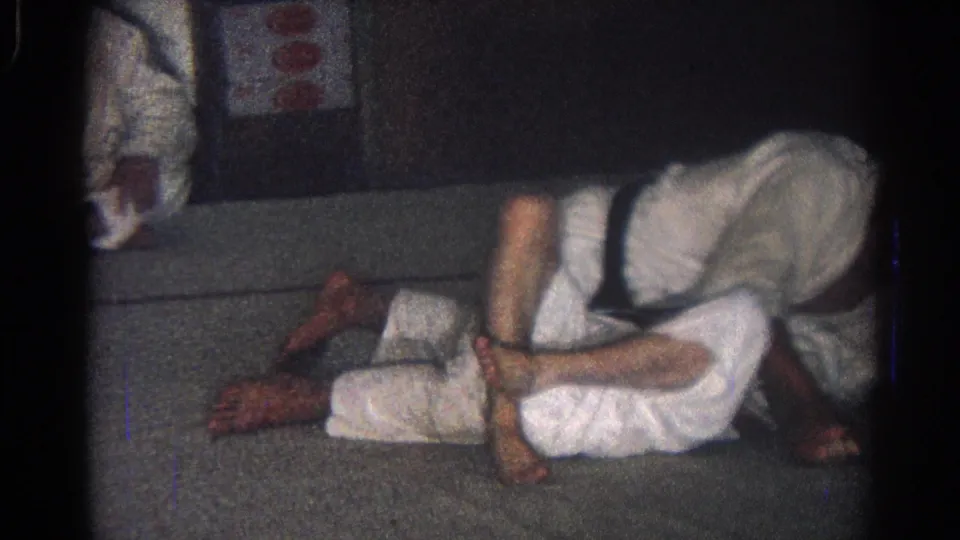 1966 San Gabriel dojo footage showing one white-gi practitioner leaning over another during a close ground grappling drill.