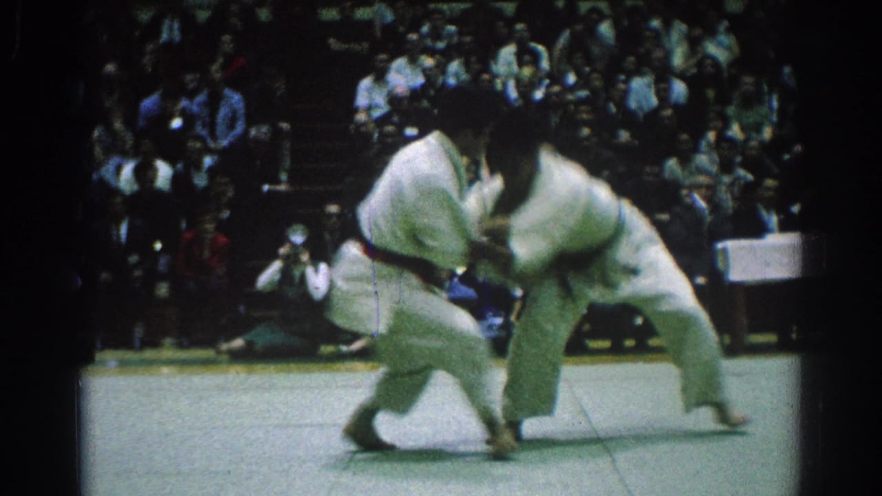 One judo competitor bends forward as the other drives in during a throw attempt.