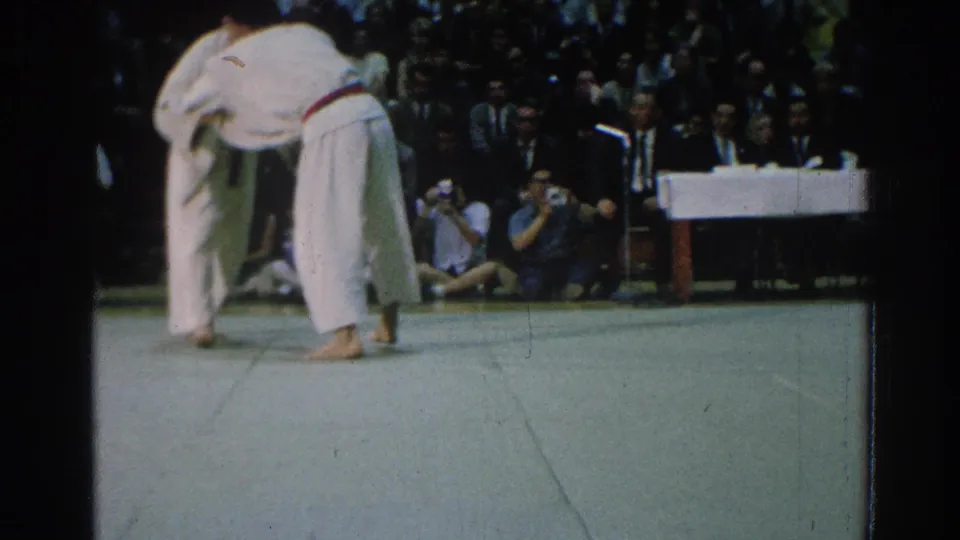A close, handheld 8mm view shows two competitors gripping during the San Gabriel martial arts competition.