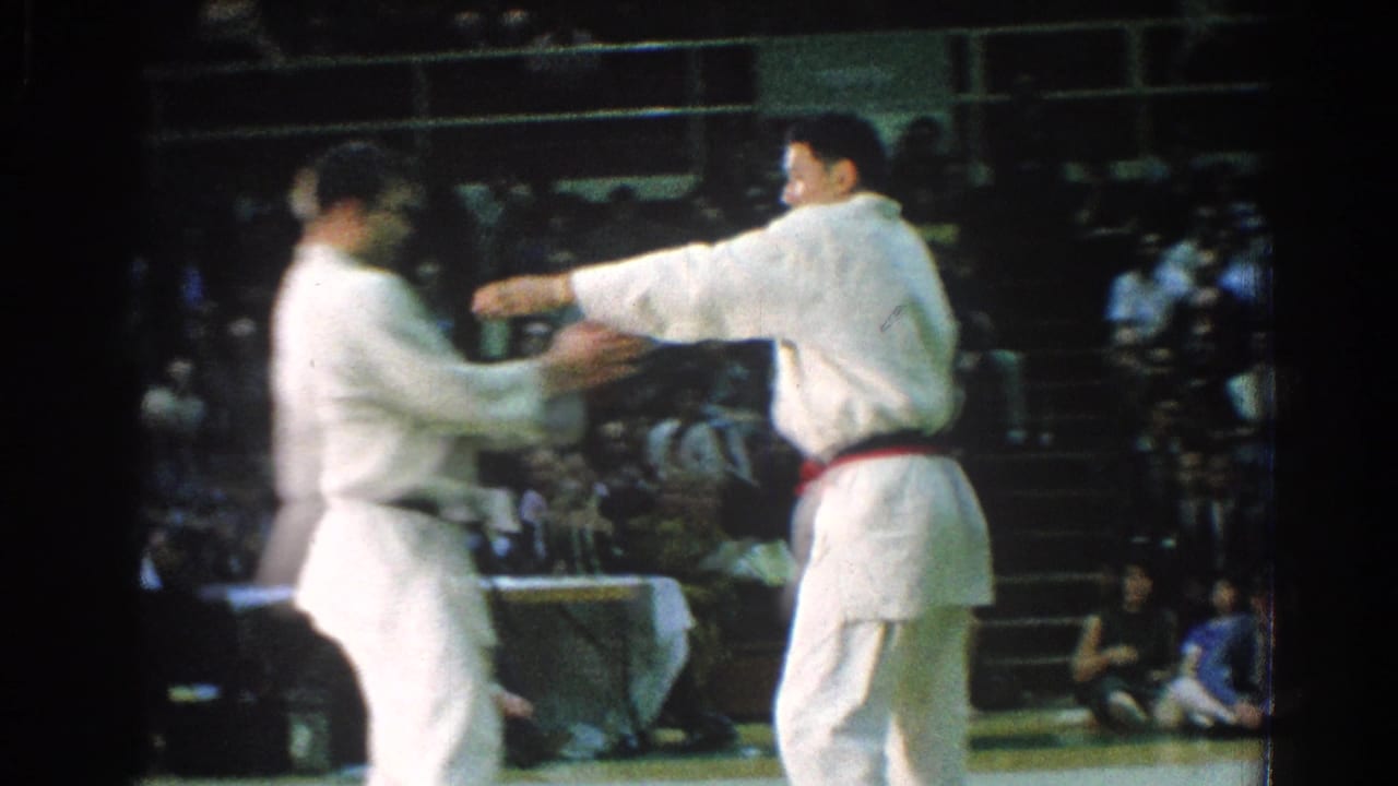 Two judo competitors in white gi uniforms face each other on a gymnasium mat.